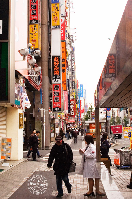 Tissue paper girl, neon signs backdrop, Shinjuku, Tokyo